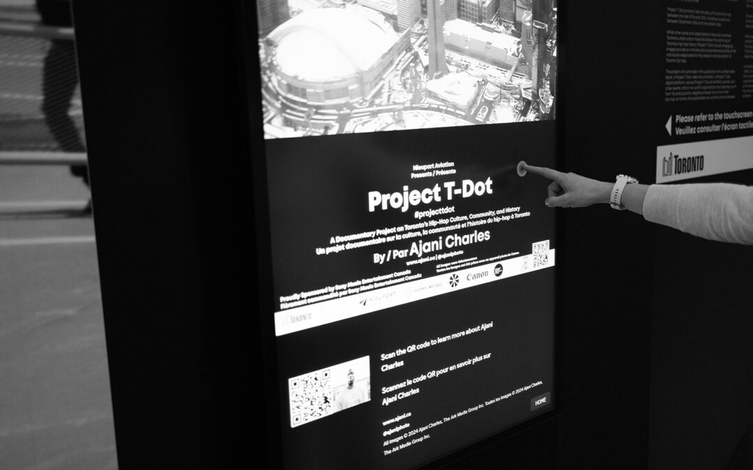 Interactive digital display of Project T-Dot, a documentary on Toronto Hip-Hop culture, at Billy Bishop Airport, with person pointing at the screen.